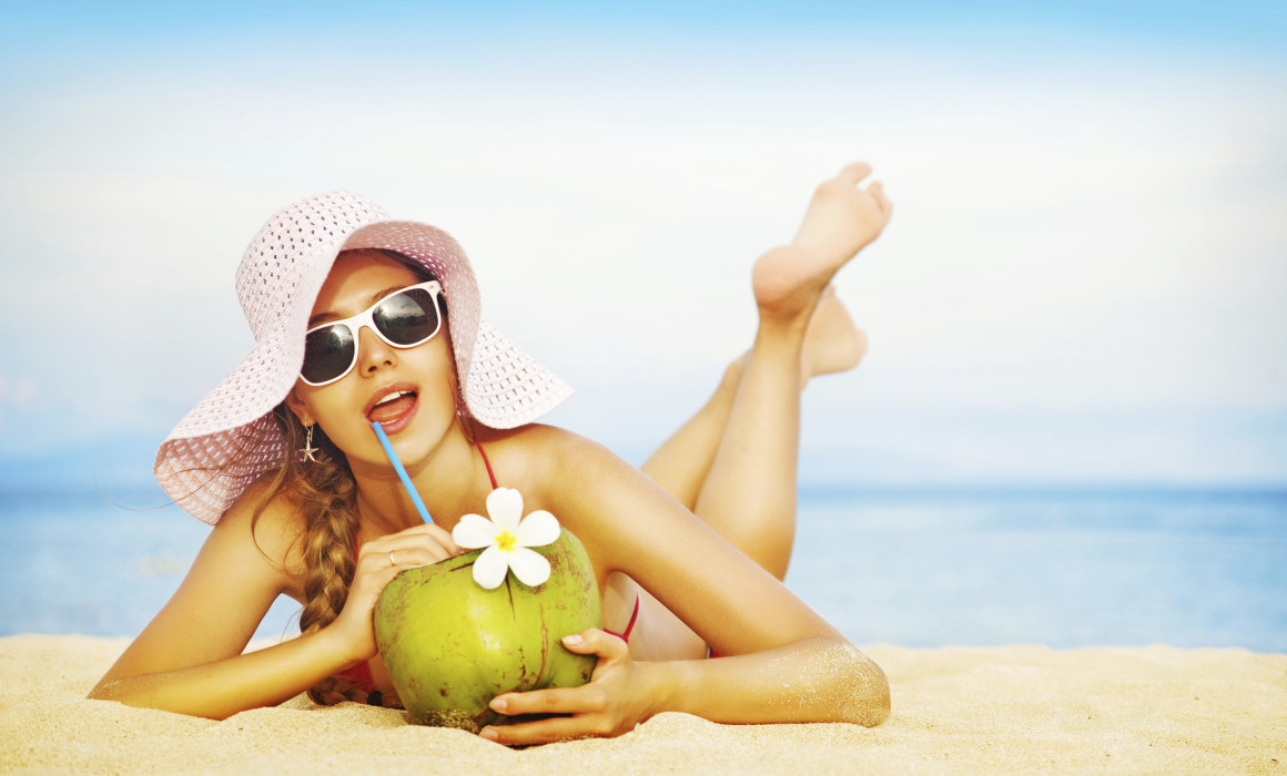 Young woman in pink swimsuit with coconut cocktail